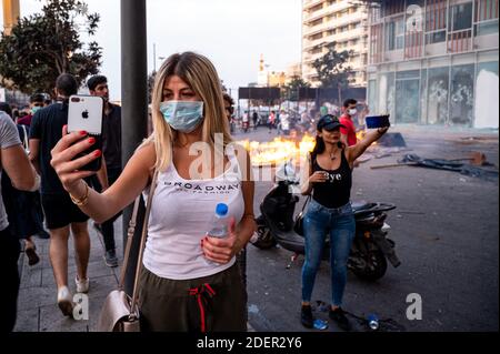 Le donne prendono selfie accanto alle gomme brucianti durante una delle proteste che si sono svolte in Downtown e di fronte alla 'Serail' o al palazzo del governo a Beirut, Libano, il 18 ottobre 2019. Le proteste si sono manifestate contro una decisione del governo di tassare le richieste fatte su ‘WhatsApp’ e altre applicazioni telefoniche, nonché contro la corruzione dei partiti politici. Foto di Ammar Abd Rabbo/ABACAPRESS.COM Foto Stock