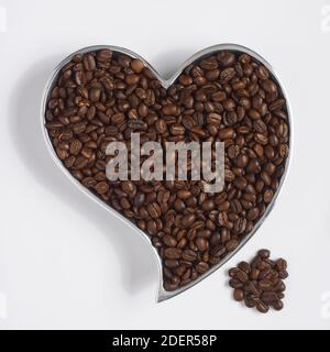 chicchi di caffè in un contenitore a forma di cuore Foto Stock