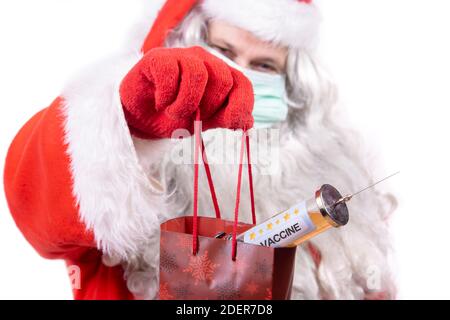 Babbo Natale con maschera viso offre regalo di Natale un vaccino iniezione. Foto Stock