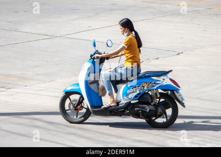 SAMUT PRAKAN, THAILANDIA, 27 2020 LUGLIO, donna con maschera faccia corre una moto Foto Stock