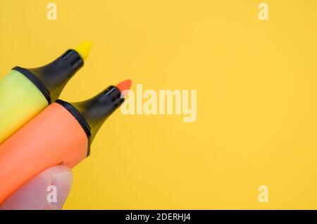 Un colpo di dita che tiene isolati due marcatori colorati uno sfondo luminoso ed Foto Stock