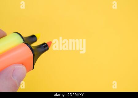 Un colpo di dita che tiene isolati due marcatori colorati uno sfondo luminoso Foto Stock