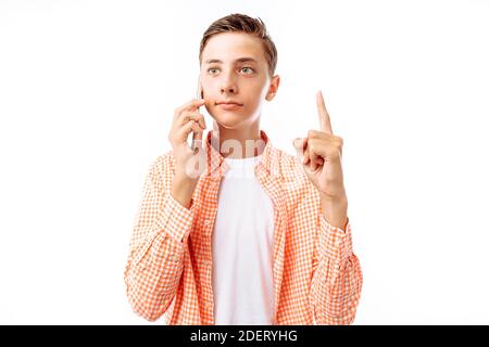 Ragazzo teenager che parlava al telefono, con libri in mano, in uno studio fotografico su sfondo bianco, il ragazzo aveva un'idea Foto Stock