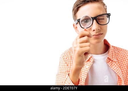 Un giovane guarda una lente d'ingrandimento nello Studio su uno sfondo bianco, spazio di copia Foto Stock