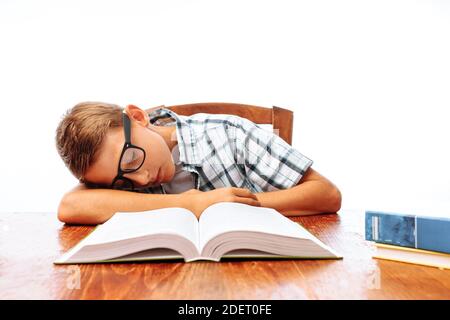 Teen guy si addormentò seduto con i libri, studente che dormiva alla scrivania in Studio Foto Stock