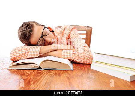 Teen guy si addormentò seduto con i libri, studente che dormiva alla scrivania in Studio Foto Stock