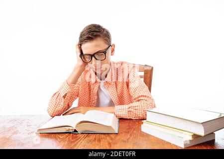 Teen guy si addormentò seduto con i libri, studente che dormiva alla scrivania in Studio Foto Stock