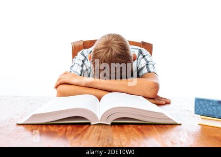 Teen guy si addormentò seduto con i libri, studente che dormiva alla scrivania in Studio Foto Stock