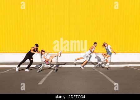 Gli amici cavalcano su carri, vicino al supermercato, un grande passatempo, un gruppo di giovani cavalcano su carri, le coppie innamorate si divertono nel tempo di Sunny Foto Stock