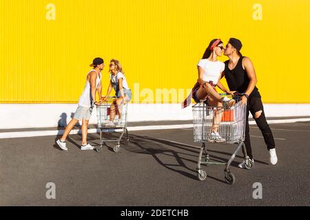 Gli amici cavalcano su carri, vicino al supermercato, un grande passatempo, un gruppo di giovani cavalcano su carri, le coppie innamorate si divertono nel tempo di Sunny Foto Stock