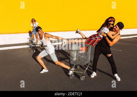 Gli amici cavalcano su carri, vicino al supermercato, un grande passatempo, un gruppo di giovani cavalcano su carri, le coppie innamorate si divertono nel tempo di Sunny Foto Stock