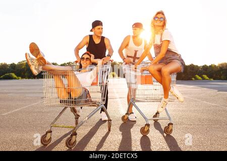 Gli amici cavalcano su carri, vicino al supermercato, un grande passatempo, un gruppo di giovani cavalcano su carri, le coppie innamorate si divertono nel tempo di Sunny Foto Stock