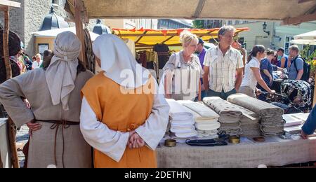 Le donne in abito medievale vendono tessuti da una stalla nella piazza centrale di Tallinn, Estonia Foto Stock