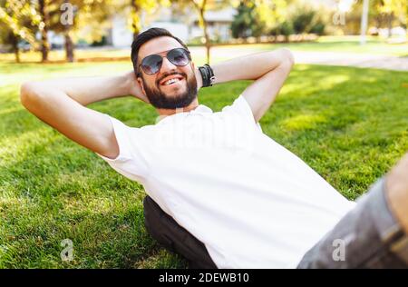 Elegante hipster in camicia bianca, riposante sul prato del Parco, di buon umore Foto Stock