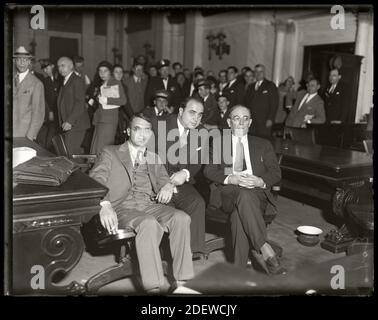 Al Capone siede in tribunale federale durante il processo di evasione fiscale con i suoi avvocati Michael Ahern, a sinistra, e Albert Fink, a destra. Chicago, Illinois, 7 ottobre 1931. Immagine da negativo vetro 4x5 pollici. Foto Stock