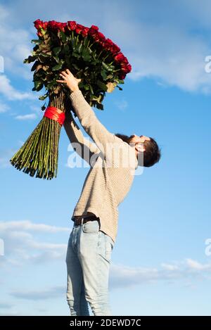 San Valentino. Uomo bello e sicuro che va in data in tuta, tenendo bouquet  di rose rosse e palloncini cuore, in piedi con regali per l'amante sopra  Foto stock - Alamy