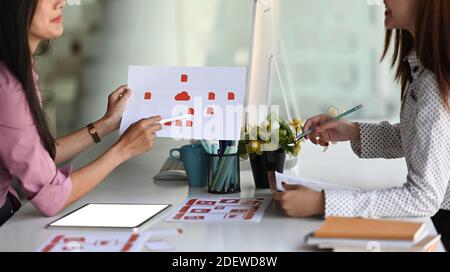 Un'immagine ritagliata dello sviluppatore di ux asiatico e del progettista dell'interfaccia utente stanno discutendo la progettazione dell'interfaccia delle app mobili durante una riunione in un ufficio moderno. Foto Stock