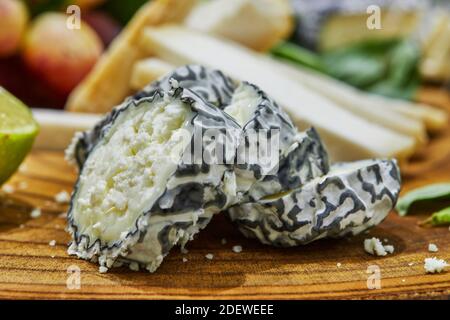 Affettare su tavola di legno formaggi selezionati con uva, lime, ananas ed erbe Foto Stock