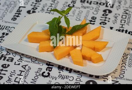 Pezzi di melone di cantalupe su un piatto. Primo piano, messa a fuoco selettiva, sfondo sfocato, concept foto cibo sano. Foto Stock