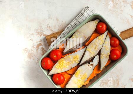 Bistecche di halibut ghiacciate in un piatto da forno con pomodori e patate dolci. Spazio di copia. Piatto di pesce. Foto Stock