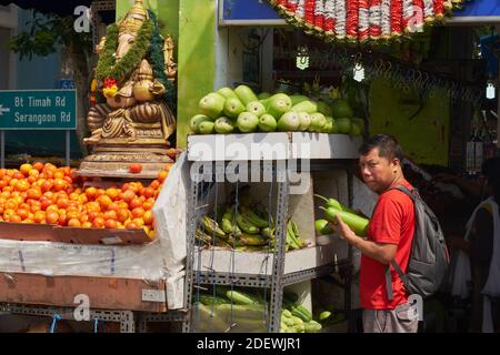 Un uomo che acquista verdure in una bancarella di verdure a gestione indiana decorata con una statua del dio degli elefanti indù Ganesh; Buffalo Road, Little India, Singapore Foto Stock