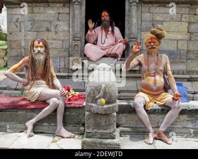 Sadhus (uomini santi indù, ascetici) al tempio di Pashupatinath, Kathmandu, Nepal, il sito indù più sacro del paese, alzando le mani in benedizione Foto Stock