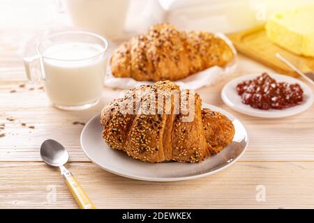 Croissant multigrein cosparso di semi serviti con latte, idea colazione Foto Stock