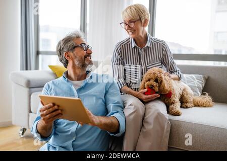 Felice coppia matura sorridente che usa il tablet digitale a casa Foto Stock