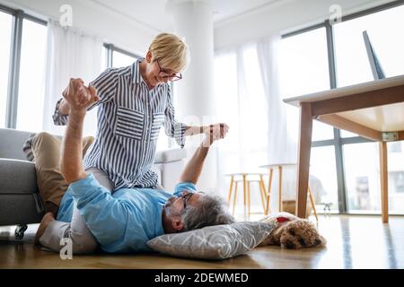 Felice coppia senior in amore abbracciando e legame con emozioni vere a casa Foto Stock