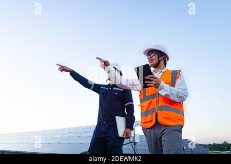 Ingegneri con investitore a piedi per controllare il funzionamento dei sistemi di fattoria solare (pannello solare), energia alternativa per conservare il mondo è energia, Photov Foto Stock