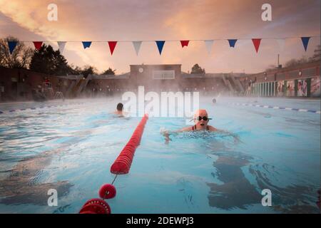 Nuotatori al mattino presto durante l'alba al Lido di Charlton a Hornfair Park, Londra, il suo primo giorno di riapertura dopo la fine della seconda chiusura nazionale e l'Inghilterra entra in un sistema rafforzato di restrizioni regionali al coronavirus. Foto Stock