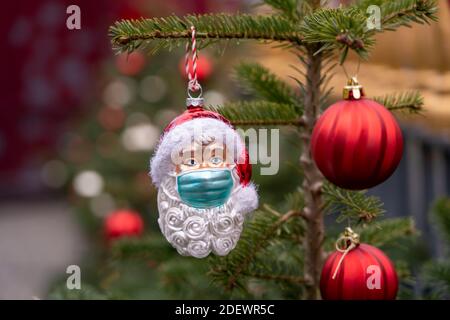 Immagine simbolica del Natale nella crisi di Corona, Padre Natale figura, Babbo Natale, decorazioni albero di Natale, con maschera bocca-naso, ma quotidiano Foto Stock