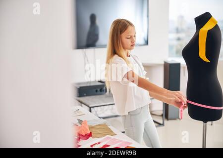 Ragazza su misura prendendo la misura dell'anca sul manichino Foto Stock