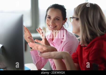 Due donne sorridenti sono sedute al computer. Foto Stock