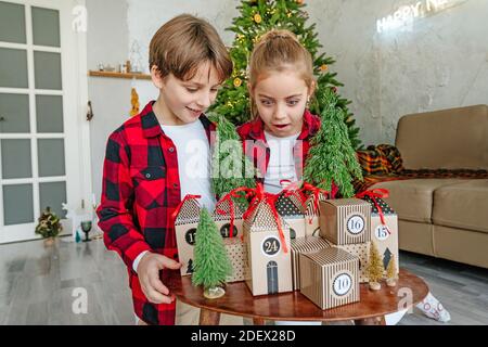 I bambini che aprono il calendario dell'avvento a mano di Natale in una forma di casa per conto alla rovescia i giorni fino a Natale in camera. Foto Stock