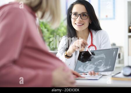Il medico femminile dimostra la scansione ecografica fetale alla donna incinta. Foto Stock