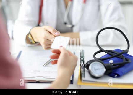 Il medico passa il biglietto da visita al paziente in un ufficio medico. Foto Stock