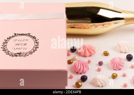 confezione regalo rosa con dolci multicolore sparsi e torta bizet su un tavolo di legno bianco Foto Stock