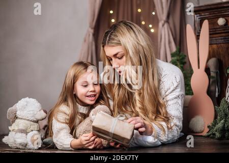 Buona madre e piccola figlia che aprono i regali di Natale Foto Stock