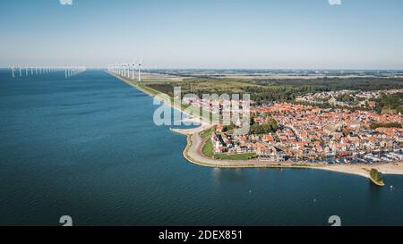 Città storica di Urk a Flevoland, nei Paesi Bassi, con una fattoria di turbine eoliche offshore sullo sfondo. Vista aerea. Foto Stock