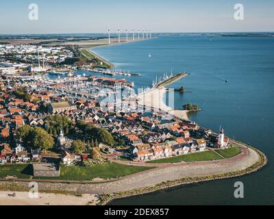 Storica città di pescatori di Urk a Flevoland, Paesi Bassi, con faro e porto, con turbine eoliche sullo sfondo. Popolare tou Foto Stock