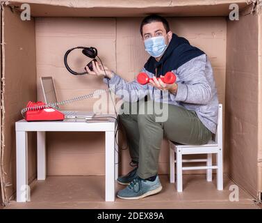 il dipendente lavora dal proprio ufficio di cartone per isolarsi da altri Foto Stock