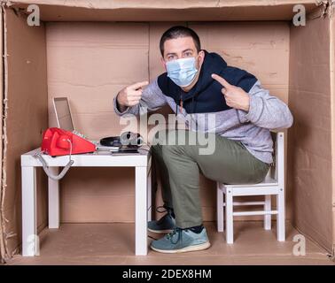 il dipendente lavora dal proprio ufficio di cartone per isolarsi da altri Foto Stock