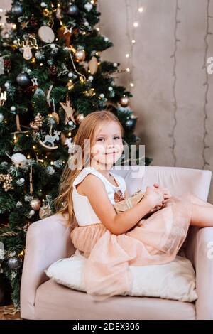 Bella bambina con regalo vicino albero di Natale a casa Foto Stock