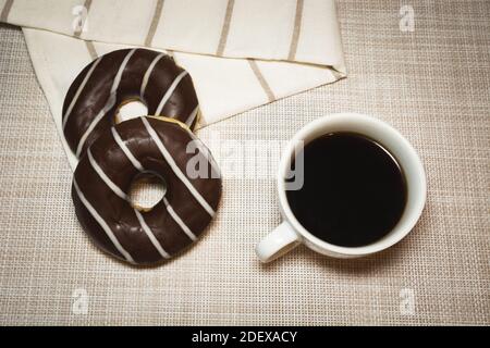 Due ciambelle di cioccolato e una tazza di caffè, vista dall'alto Foto Stock