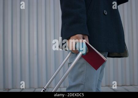 Uomo irriconoscibile vicino con valigia e passaporto in mano. Cammina direttamente verso l'aeroporto con un caffè take away durante Covid 19. Foto Stock