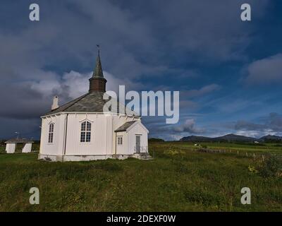 Storica chiesa in legno costruita in stile ottagonale con facciata dipinta di bianco tra prati verdi vicino al villaggio di Dverberg sull'isola di Andøya, Norvegia. Foto Stock