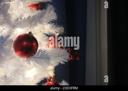 Baubles rossi di natale appesi all'albero bianco di natale. Foto Stock