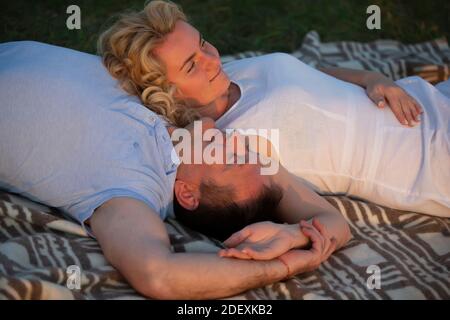 Una bella coppia di mezza età innamorata giace sull'erba. Un uomo e una donna riposano in natura. Foto Stock