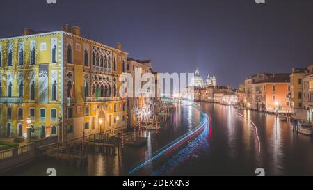 Vista sul Canal Grande di notte a Venezia con sentieri di luci dalle barche di passaggio Foto Stock